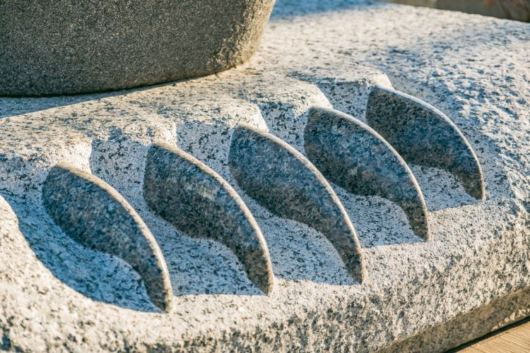 Photo of Five stone bear claws at the base of the residential school monument.