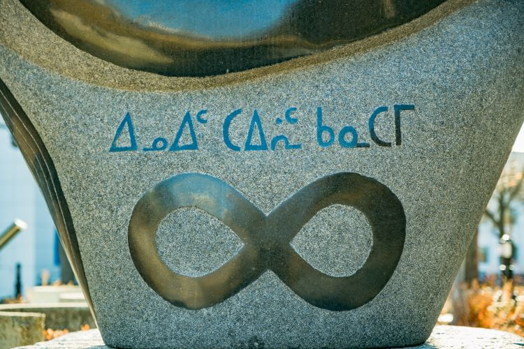 Photo of the Residential school monument showing the name of the Inuit national political organization, written in Inuktitut, and the infinity figure 8 symbol, representing the Métis symbol.