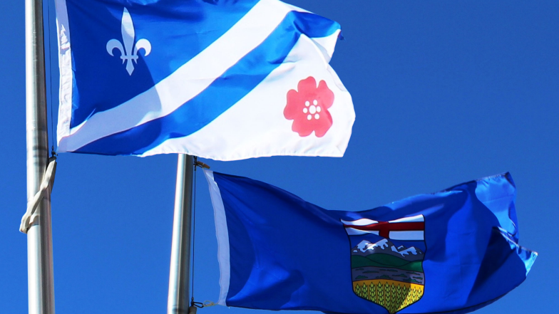 Photo of the Franco-Albertan and Alberta flag flying against a blue sky
