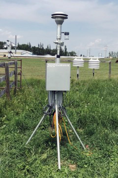 Portable Environmental Beta Attenuation Mass (E-BAM) monitor in a field under a cloudy blue sky