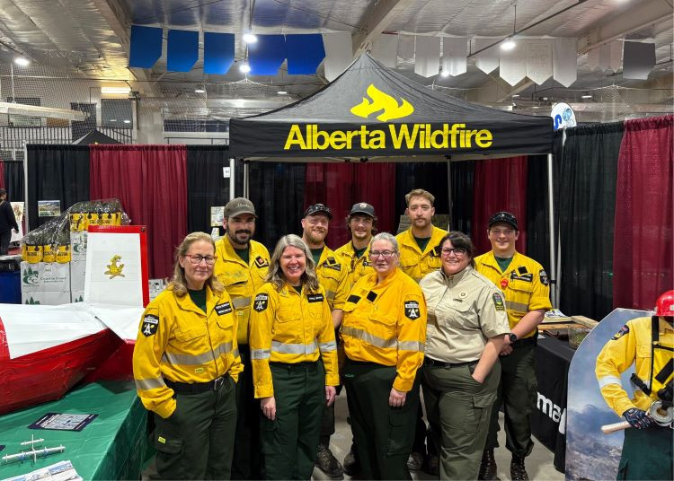 A group of wilfire firefighters are standing in front of their booth at the Edson tradeshow.