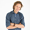 Joal stands with his arms crossed, smiling.