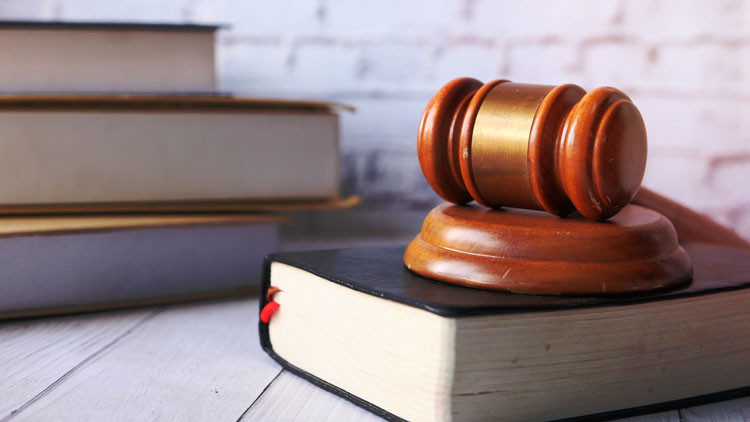 Wooden gavel on a black book with books in the background