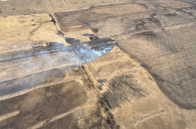 A wildfire in farm fields with emergency crews responding