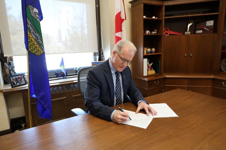 Environment and Protected Areas Minister Grant Hunter signing the Canada-Alberta Cooperation Agreement on Environmental and Impact Assessment