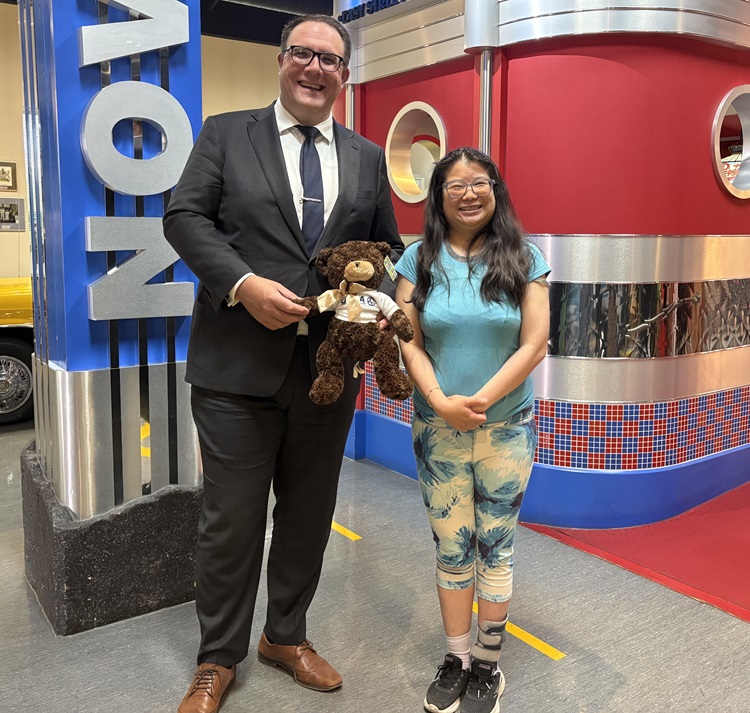 Brain injury survivor Mimi Tang presents Minister Jason Nixon with a Universal Rehabilitation Service Agency teddy bear.
