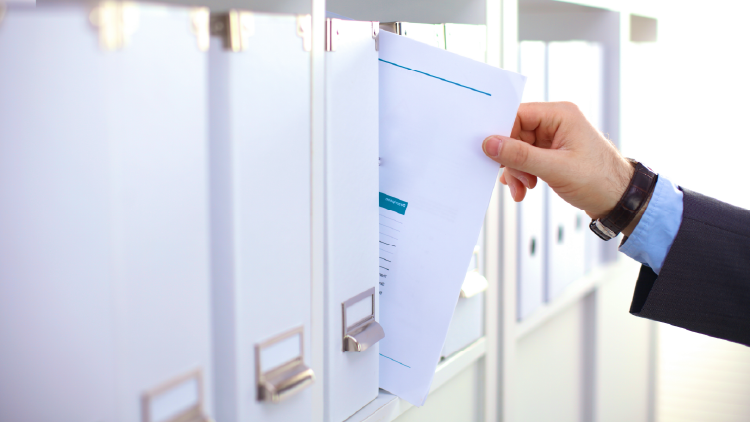 Hand pulling a paper out of a rack of files