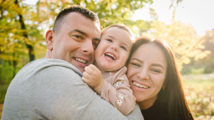 Man and woman hugging a young girl in between them between their faces