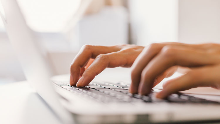 Hands typing on a laptop.