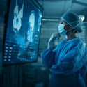 A doctor in scrubs examines an MRI scan.