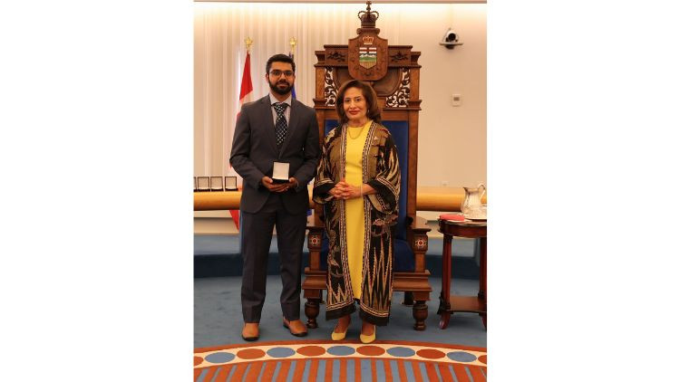 Award recipient Baber Akhtar receives a medal during a presentation ceremony in the Alberta Legislature chamber.