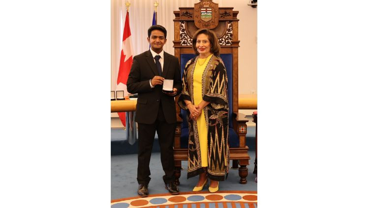 Award recipient Jerome Jacob receives a medal during a presentation ceremony in the Alberta Legislature chamber.