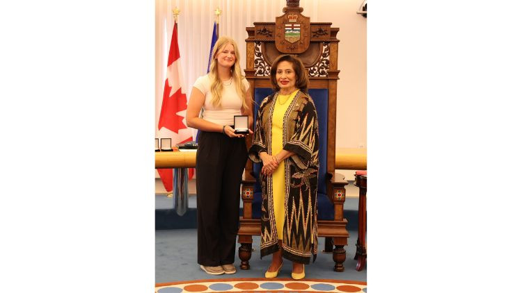 Award recipient Kate Hadwin receives a medal during a presentation ceremony in the Alberta Legislature chamber.