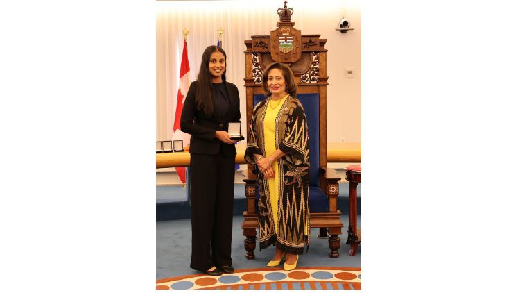 Award recipient Nishka Rai receives a medal during a presentation ceremony in the Alberta Legislature chamber.