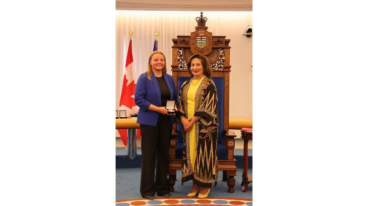 Award recipient Natasha Murphy receives a medal during a presentation ceremony in the Alberta Legislature chamber.
