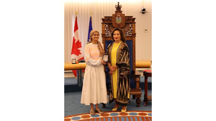 Award recipient Ameena Taher receives a medal during a presentation ceremony in the Alberta Legislature chamber.