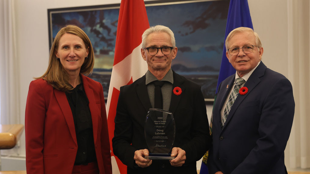Doug stands holding his award between Sherri Wilson, Deputy Minister of Advanced Education and previous inductee, Ray Massey.