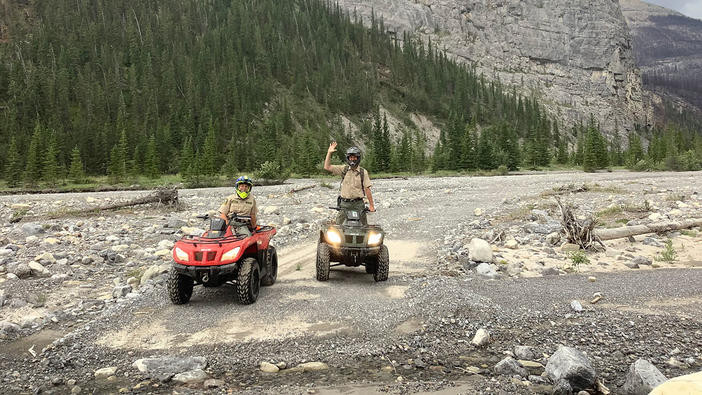 Conservation officers riding quads on patrol along a gravel trail in Alberta’s Ghost Public Land Use Zone.