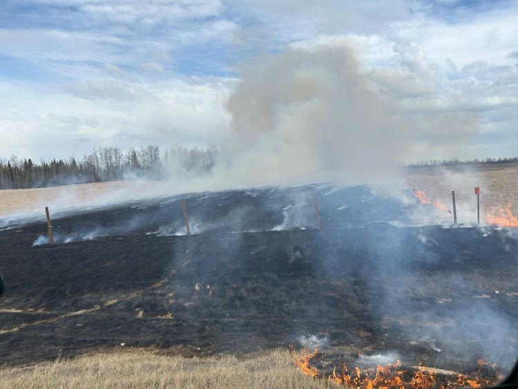 A grass fire burns in a pasture. 