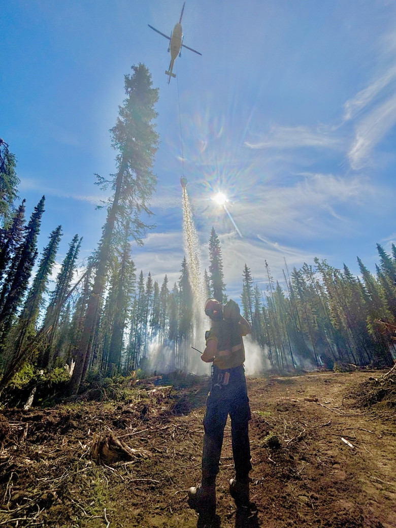 A firefighter guides a bucketing helicopter on HWF036 (July 2, 2025)