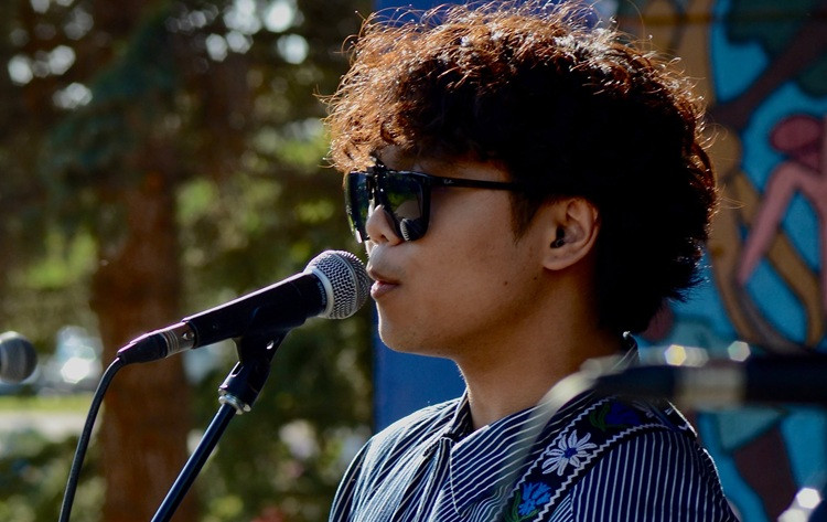 Young performer stands in front of a microphone singing on stage.
