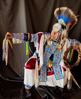 An Indigenous hoop dancer poses in traditional Indigenous clothing.