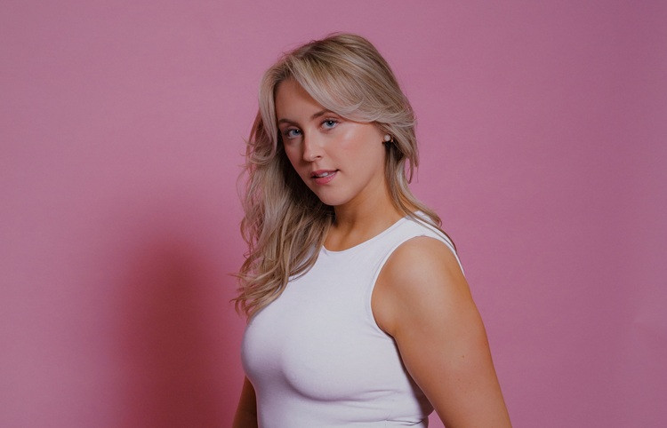 Performer stands in front of a pink wall.