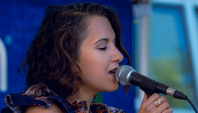 Performer holds a microphone and sings with her eyes closed.