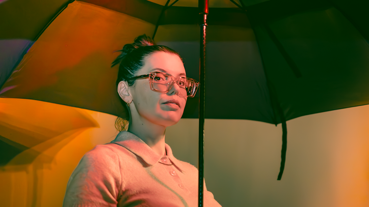 Performer stands under an umbrella.