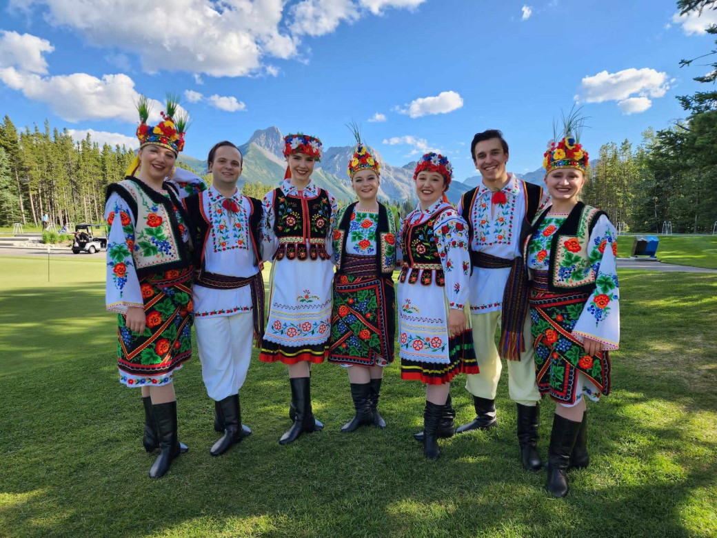 Tryzub Ukrainian Dance Ensemble stand together on green grass. 