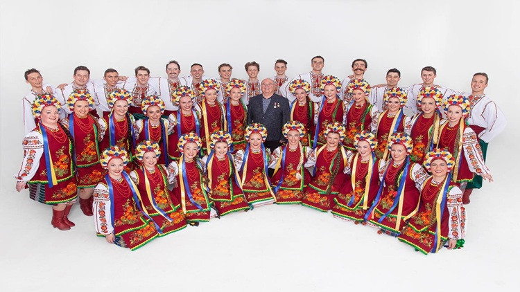 Large dance group pose for photo in colourful clothing.