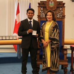 Award recipient Jerome J. receives a medal during a presentation ceremony in the Alberta Legislature chamber.