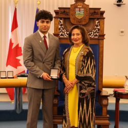 Award recipient Kamram Shukoor receives a medal during a presentation ceremony in the Alberta Legislature chamber.
