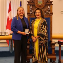 Award recipient Natasha M. receives a medal during a presentation ceremony in the Alberta Legislature chamber.