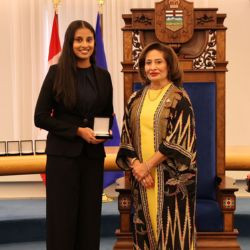 Award recipient Nishka R. receives a medal during a presentation ceremony in the Alberta Legislature chamber.