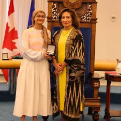 Award recipient Ameena T. receives a medal during a presentation ceremony in the Alberta Legislature chamber.
