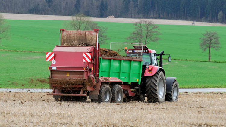 Tractor pulling manure spreader in a field