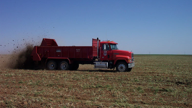 Red truck spreading manure in a field