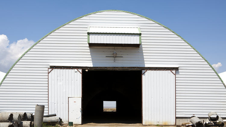 White quonset structure with 2 large sliding doors open