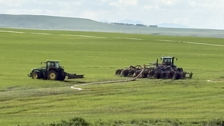 Two tractors spreading manure in a green field