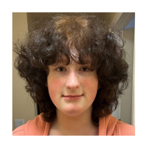Adoption profile photo of Karina - young girl with curly brown hair in an orange top