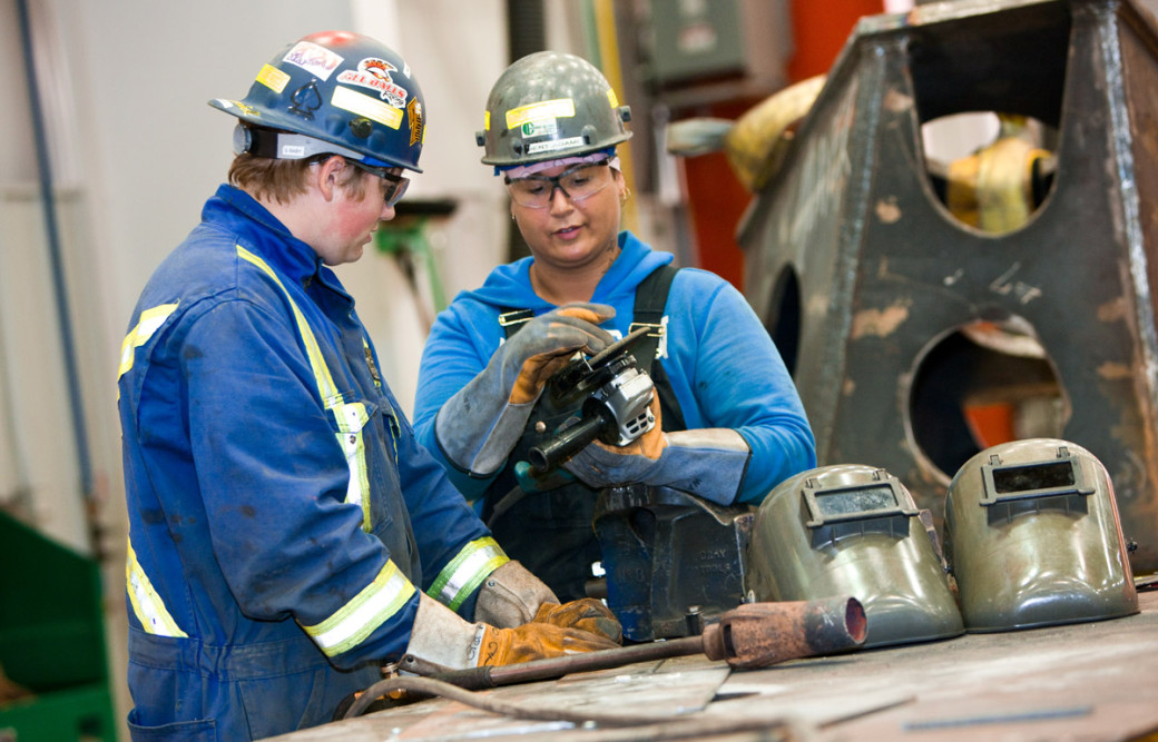 Two young tradespeople work on a welding project