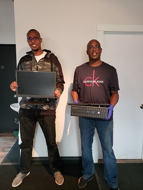 Two of KULAN Community and Youth Development holding computers