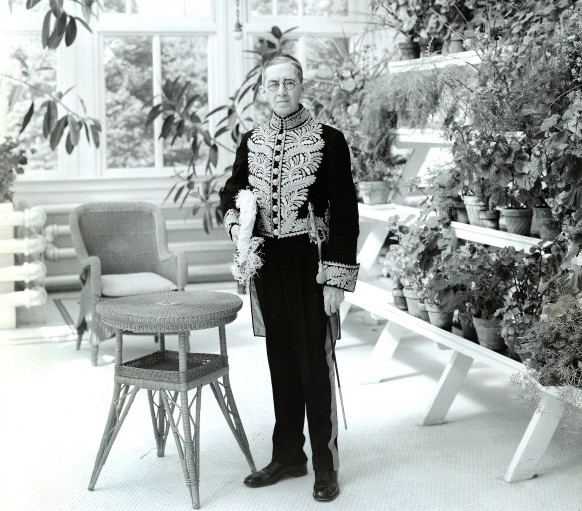 The Lieutenant Governor, standing by a table in a conservatory in full regalia.
