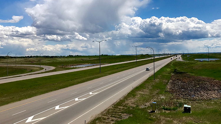 Calgary ring road - freeway surrounded by grass and blue sky with white clouds
