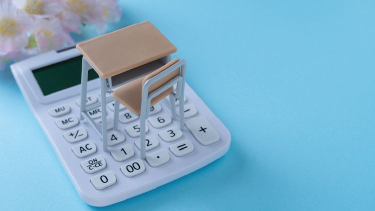 School desk and calculator. Image of tuition fees.Cherry blossom and blue background.