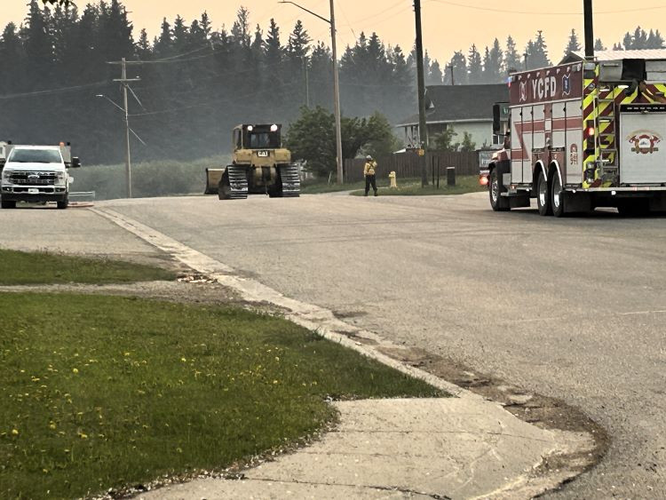 Truck, dozer and firetruck on a paved road.