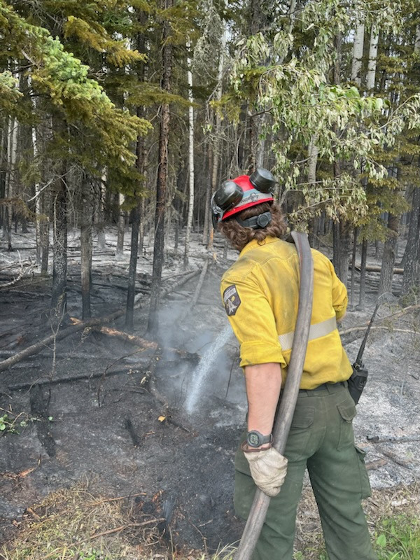 Firefighter spraying water on the ground.