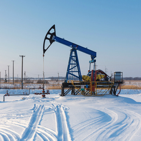 Pumpjack in a snowy field on a clear winter day