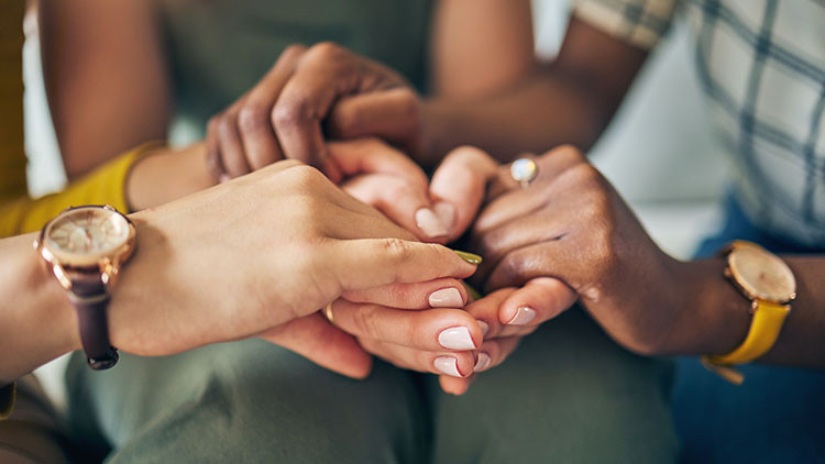 Group of people all holding hands and supporting each other.